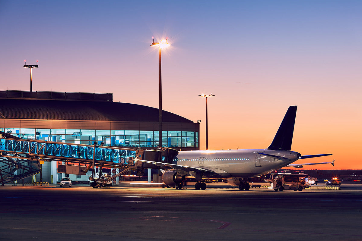 Airplane and Jet Bridge at Airport at Sunset